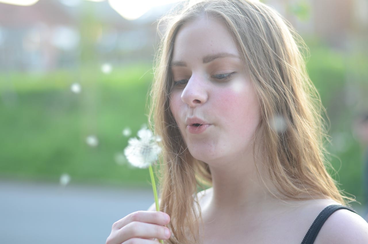 Girl blowing on dandelion