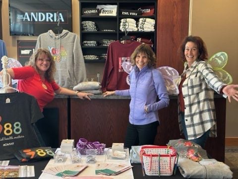 Dragonfly board members posing in front of apparel at our 2024 gift wrapping fundraiser.  